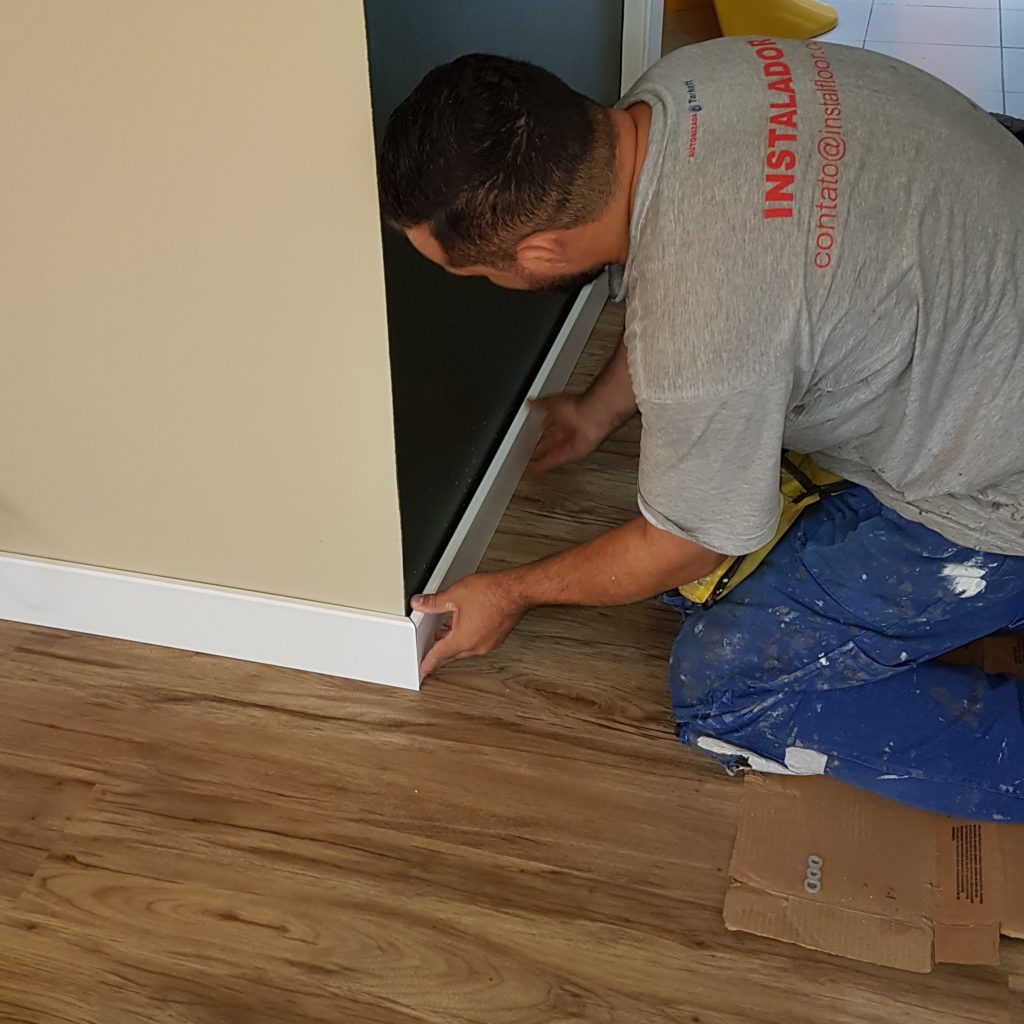 Instalador da Instalfloor fixando rodapé sobre piso vinílico